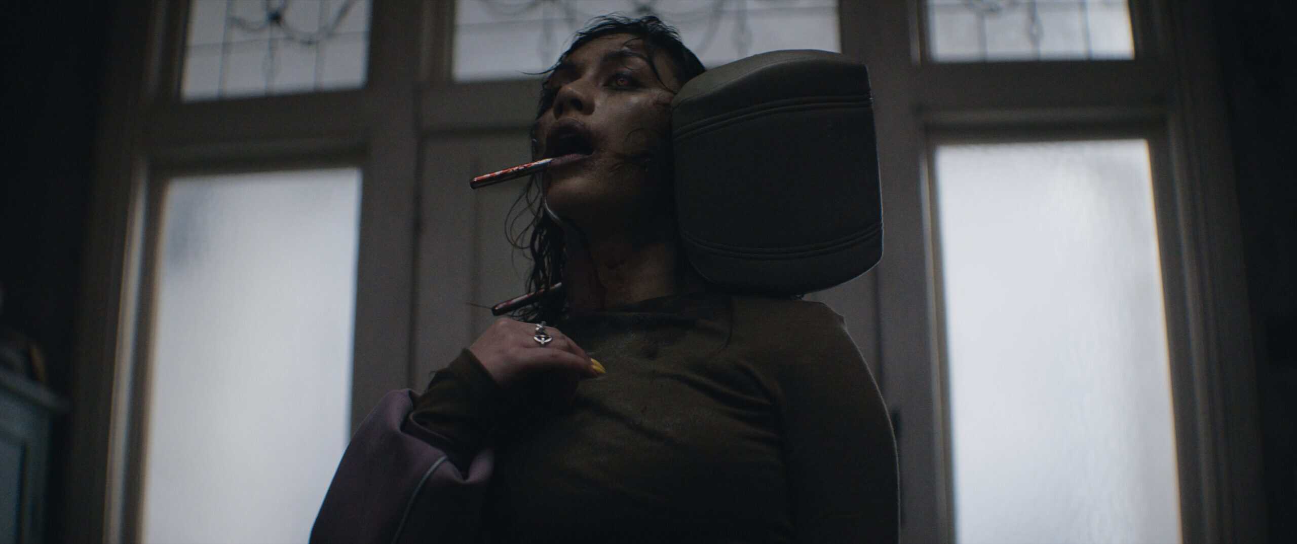 Luciane Buchanan as Thya in Evil Dead Burn. Thya is possessed and has a car seat headrest rod coming out of her mouth.