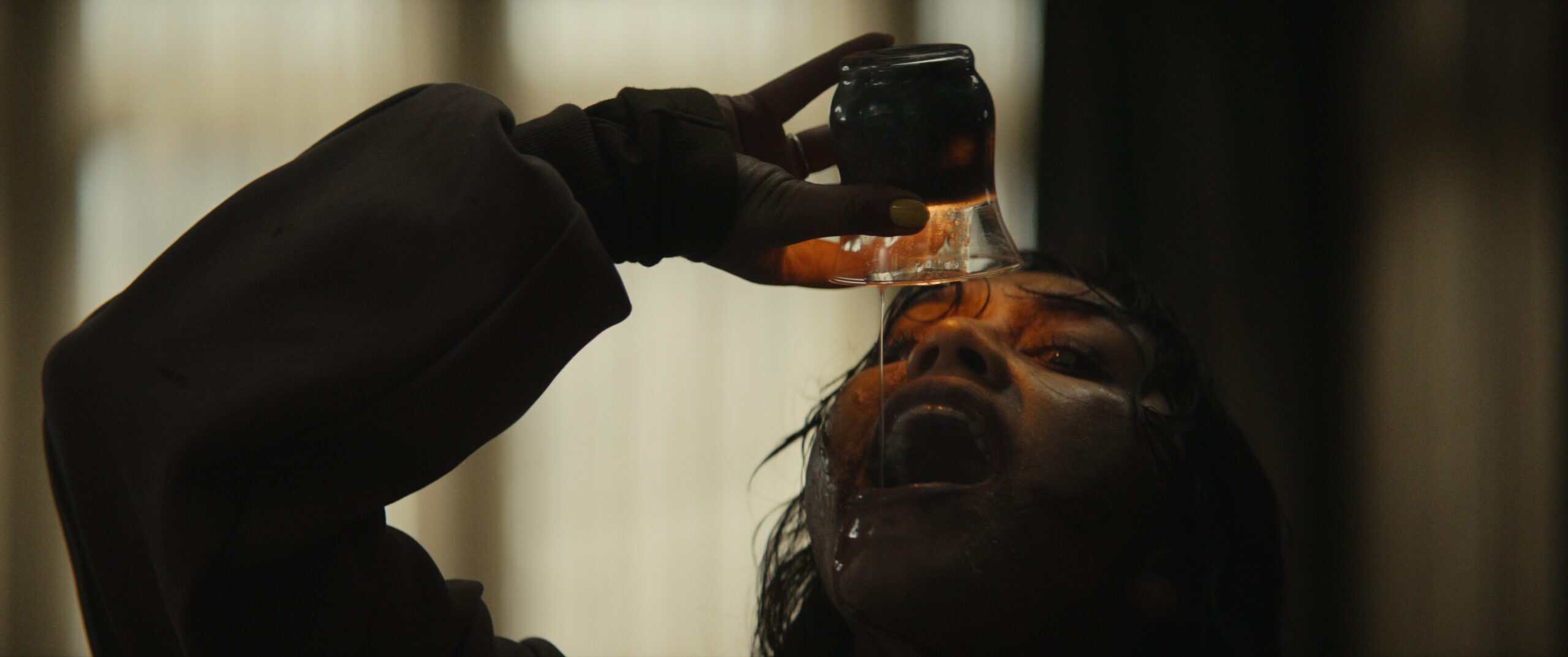 Gory scene from Evil Dead Burn with Thya, played by Luciane Buchanan, drinking hot wax from a lit candle.