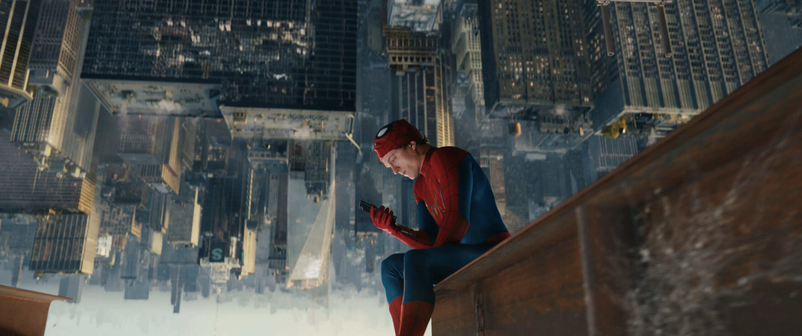 Tom Holland as Peter Parker/Spider-Man in a scene of Spider-Man: Brand New Day. The character sits on a crane above NYC's skyscrapers and looks at his phone.